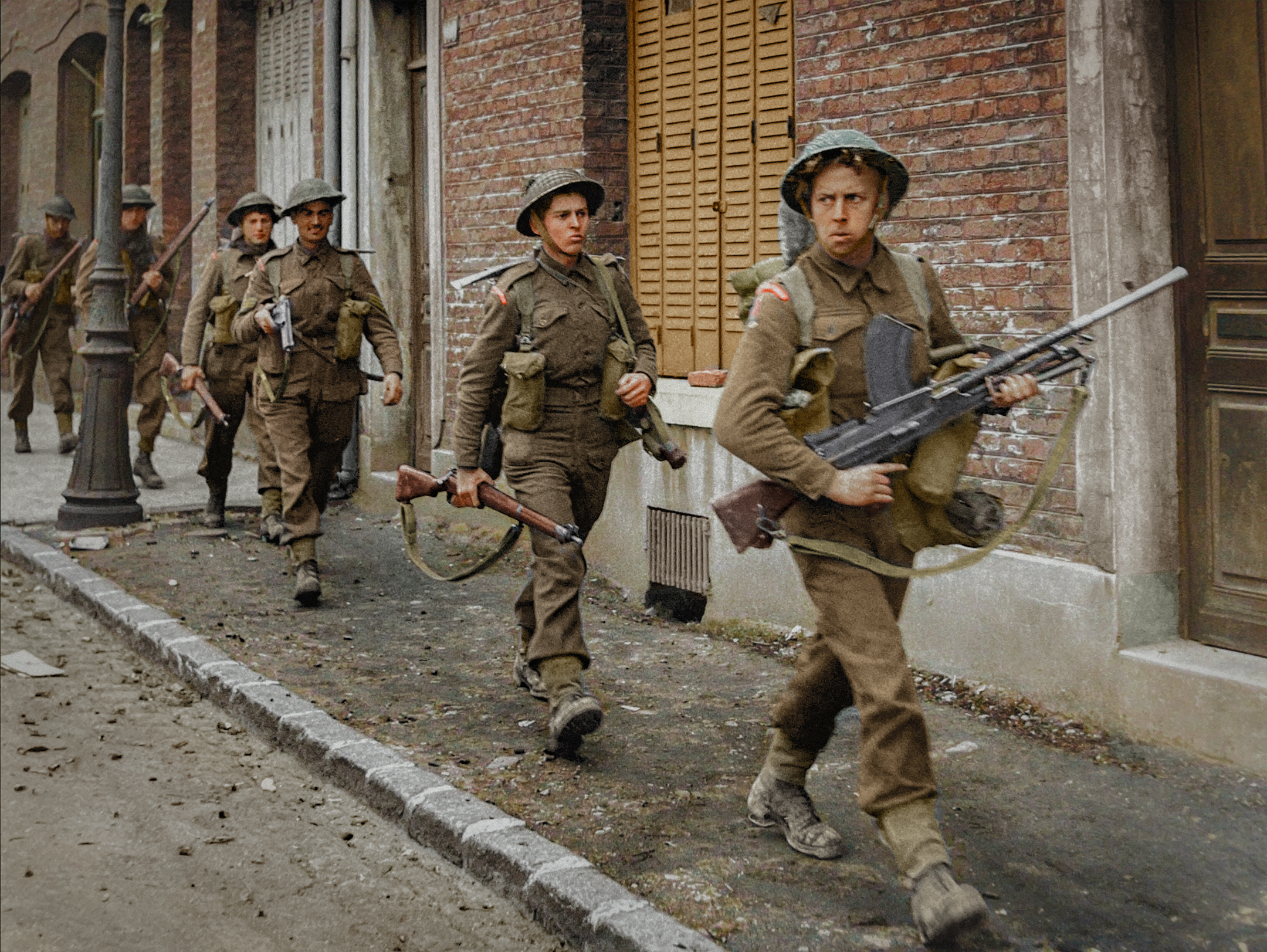 Un soldado británico con una ametralladora Bren lidera a las tropas a través de un pueblo francés